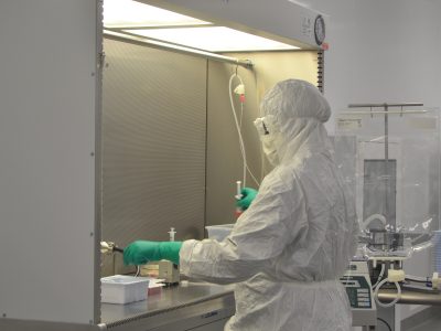 Lab technician dressed in clean room PPE working with syringes